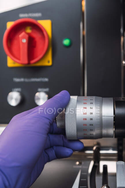 Especialista em laboratório sem rosto em luvas de látex ajustando o poderoso botão de microscópio enquanto trabalhava em laboratório moderno — Fotografia de Stock