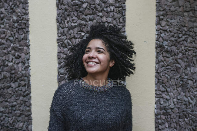 Entzückte ethnische Frau mit Afro-Frisur steht auf der Straße und schaut weg — Stockfoto