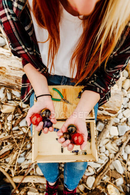 From above of crop unrecognizable craftswoman sitting with round polished semiprecious stones in nature — Stock Photo