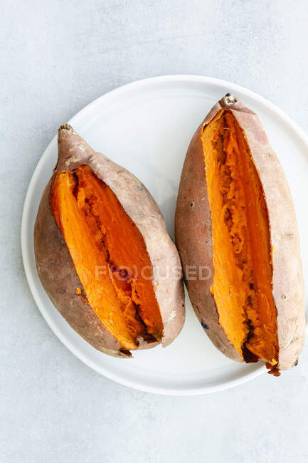 Von oben appetitliche frisch gebackene Süßkartoffeln auf weißer Keramik-Untertasse auf dem Tisch — Stockfoto