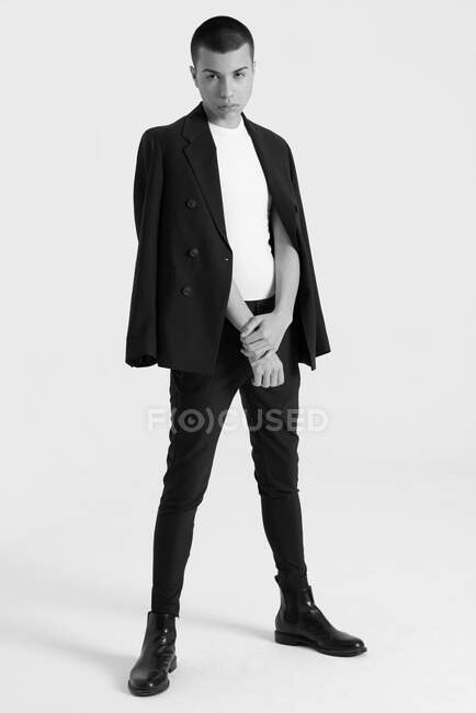 Modelo masculino sério em terno elegante em pé sobre fundo branco no estúdio e olhando para longe — Fotografia de Stock