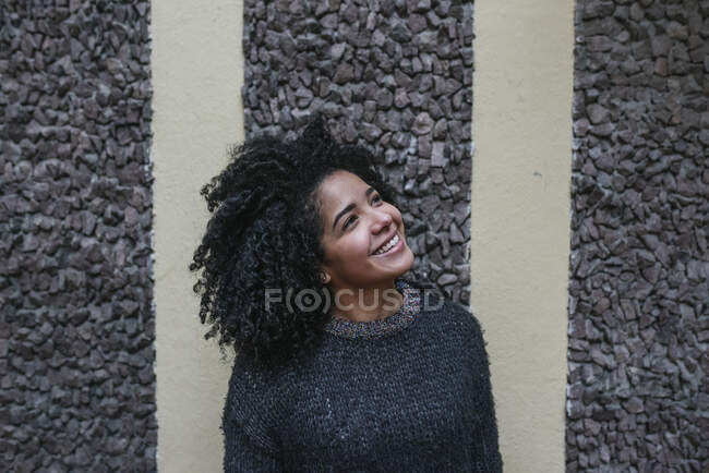 Entzückte ethnische Frau mit Afro-Frisur steht auf der Straße und schaut weg — Stockfoto