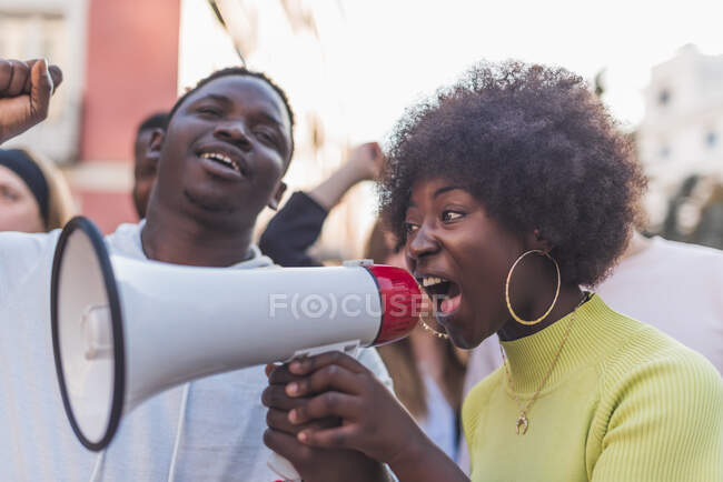 Seitenansicht eines Afroamerikaners in weiblichen Schreien in Megafon, während er gegen Rassendiskriminierung während der Demonstration 