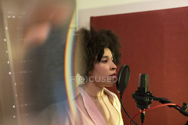 Chanteuse noire chantant une chanson contre microphone avec filtre pop tout en étant debout et impatiente en studio sonore — Photo de stock