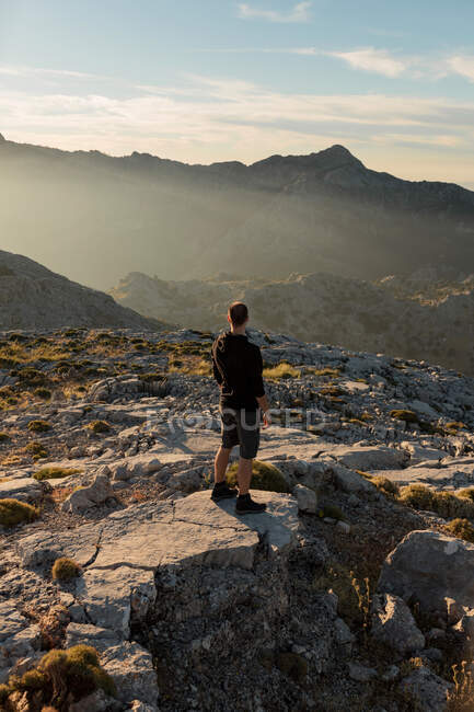 Indietro vista anonimo escursionista maschile in abbigliamento casual riposo sulla cima rocciosa montagna e ammirare viste panoramiche su altopiani grezzi a Siviglia Spagna — Foto stock