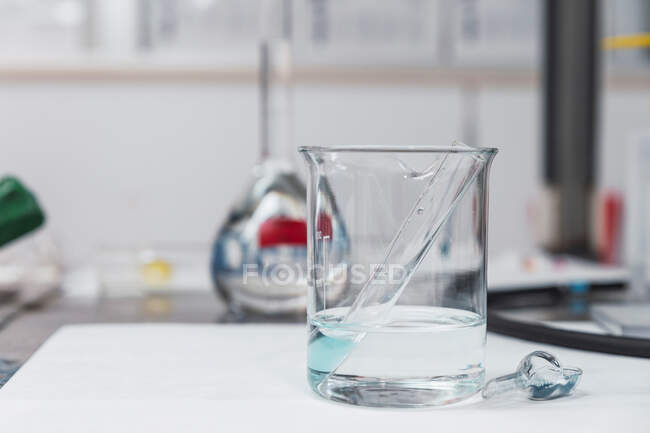 Tubo de ensaio com fluido químico azul colocado em água fria em frasco de vidro em laboratório moderno equipado — Fotografia de Stock