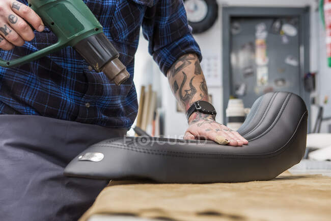 Erntehelfer mit Heißluftpistole bei der Herstellung von Lederpolstern für Motorradsitze in der Werkstatt — Stockfoto