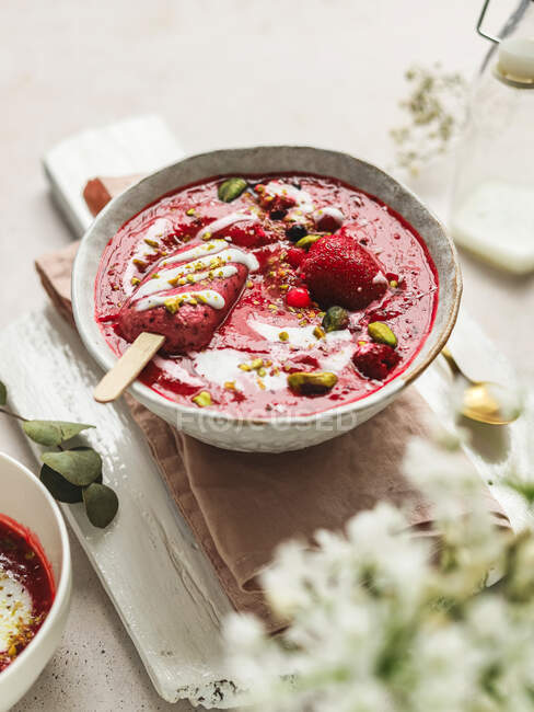 From above of tasty smoothie with fresh berries and ice candy with crushed pistachios and yogurt in bowl — Stock Photo
