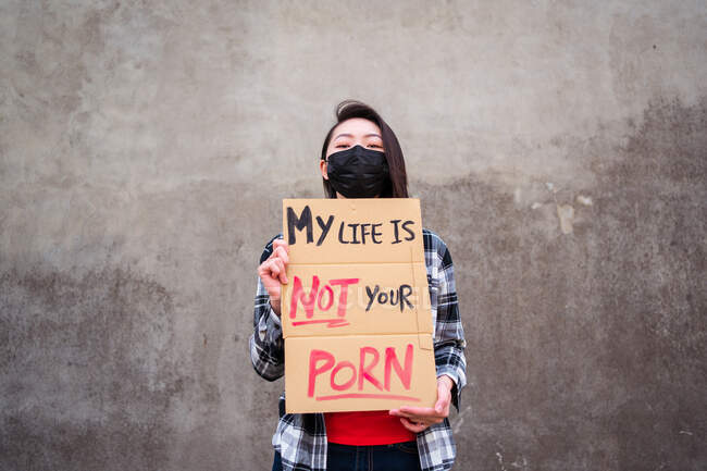Етнічна жінка в захисній масці, що стоїть з моїм життям це не твій портфель плакат під час захисту від сексуальних домагань та нападу — стокове фото