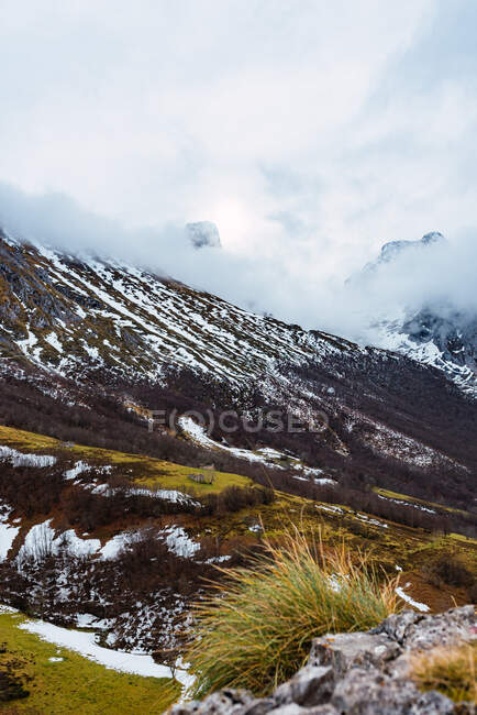 Champs verts pittoresques avec neige dans la vallée des Pics d'Europe sous un ciel nuageux lourd en Espagne — Photo de stock