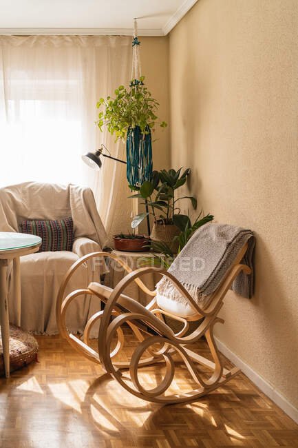 Порожня кімната з кріслом-качалкою і кріслом проти столу і рослин в будинку в сонячний день — стокове фото
