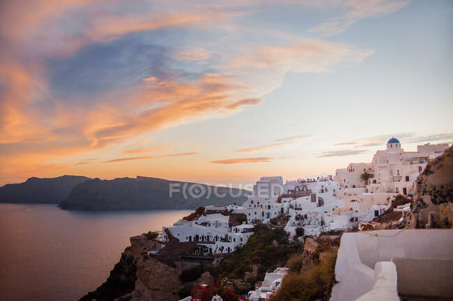 Scenic view of small coastal town with white authentic houses near tranquil sea at sunset — Stock Photo