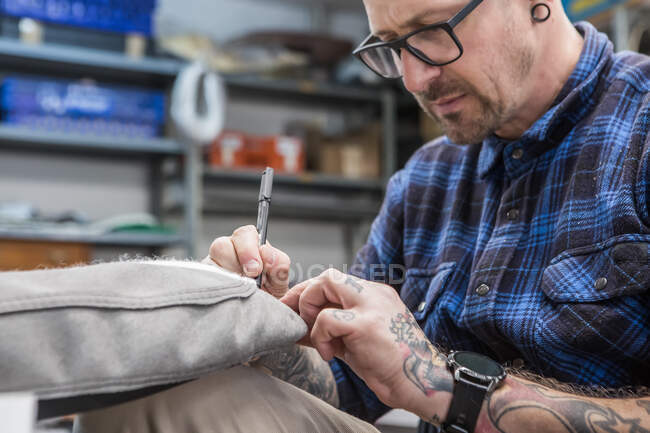 Cultiver artisan mâle avec stylo tissu de marquage de tapisserie d'ameublement pour siège de moto tout en travaillant en atelier — Photo de stock