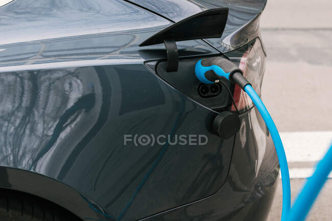 Modern eco friendly alternative EV automobile being charged with power supply plugged in at station — Stock Photo