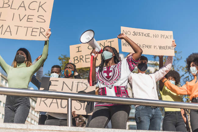 From below of crowd of multiracial protesters with placards and megaphone standing on street during Black Lives Matter protest — Photo de stock