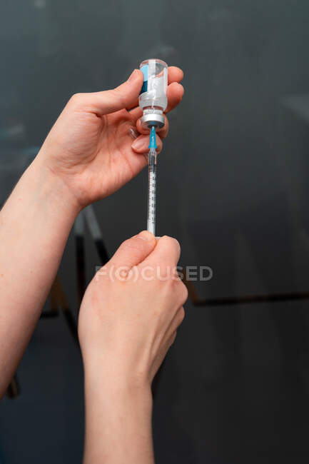 Обрізана невизначена жінка-ветеринар, яка приймає ліки з інжектором з пляшки — стокове фото