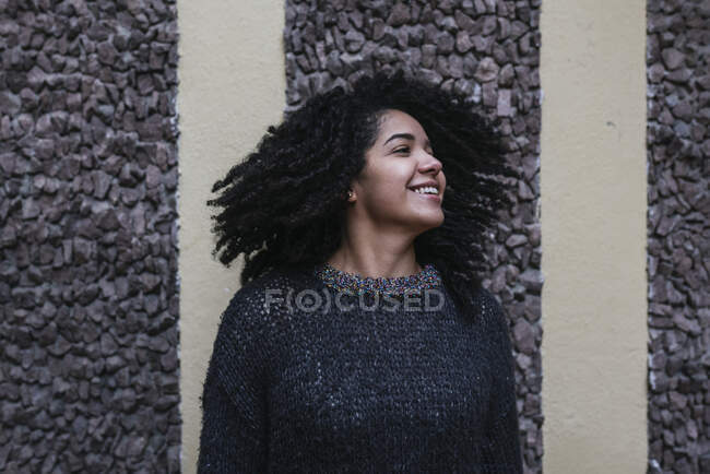 Content ethnic female with Afro hairstyle throwing hair while standing on street and smiling — Photo de stock