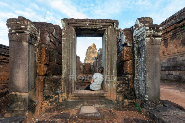 Back view of anonymous female traveler contemplating old Angkor Wat with weathered columns in Cambodia — Stock Photo