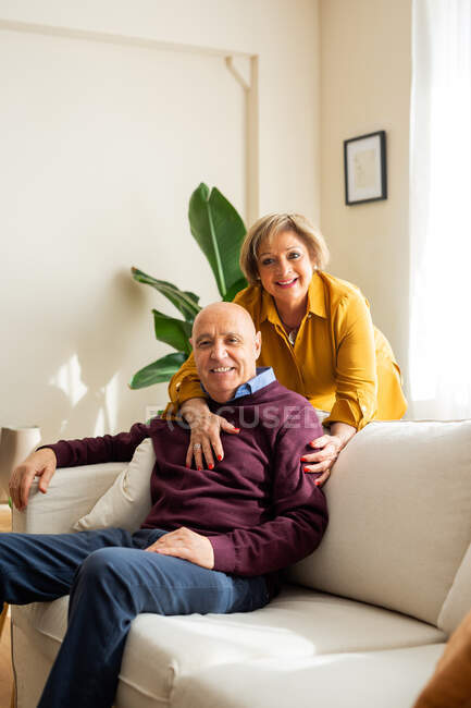 Couple d'âge moyen positif s'amuser dans le salon tout en passant du temps ensemble à la maison — Photo de stock