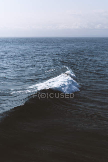 У сонячний день під блакитним небом прокочуються криві морські хвилі. — стокове фото