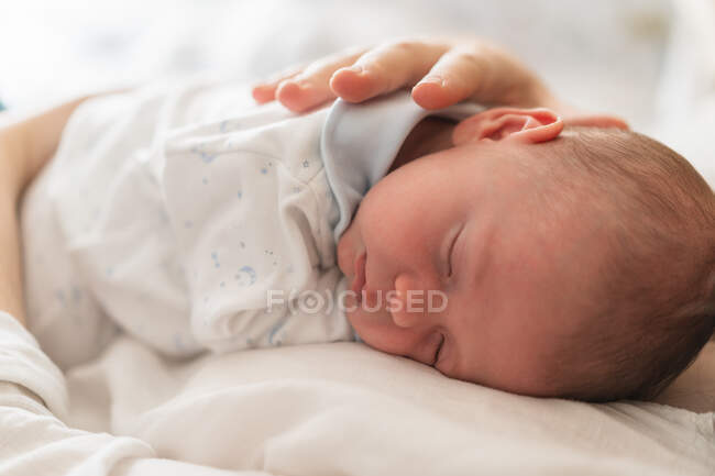 Ernte anonymer Elternteil hält niedlich schlafendes Neugeborenes zu Hause auf verschwommenem Hintergrund — Stockfoto