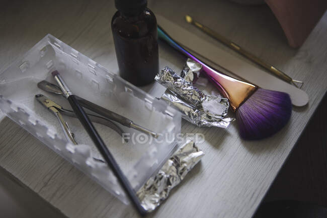 From above of various brushes with file placed on table with foils and nail clippers in beauty salon — Fotografia de Stock