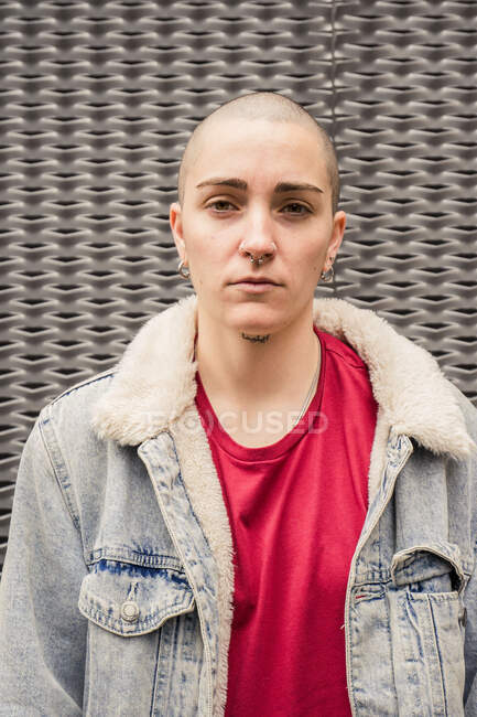 Transgênero pessoa em casaco de ganga com pele e brincos olhando para a câmera à luz do dia — Fotografia de Stock