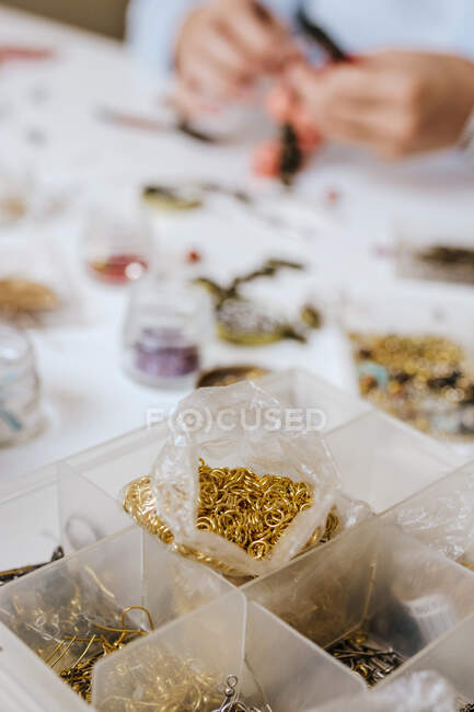 High angle of crop anonymous female designer sitting at table with different types of beads — Stock Photo