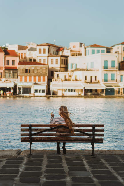 Back view faceless female traveler resting on bench on old historic town canal promenade in Chania Crete — Stock Photo