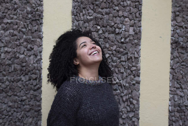 Delighted ethnic female with Afro hairstyle standing on street while look up — Foto stock