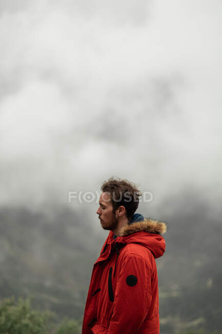 Side view thoughtful male hiker in outerwear standing on mountain summit in highlands in Seville on overcast misty weather — Stock Photo