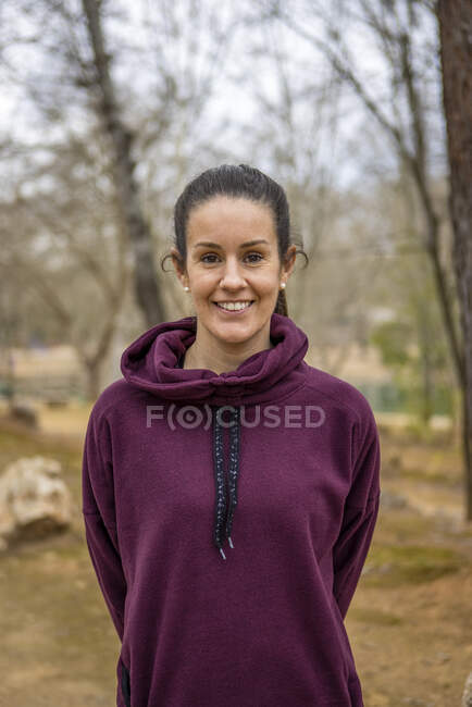 Erwachsene zufriedene Weibchen in weicher Kleidung blicken mit zahmem Lächeln auf verschwommenem Hintergrund in die Kamera — Stockfoto