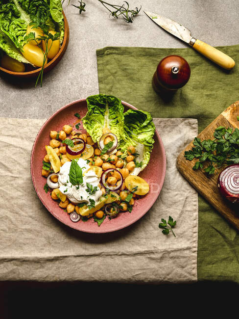Vista superior de grão de bico apetitoso com queijo burrata e legumes variados e ervas servidas no prato na mesa — Fotografia de Stock
