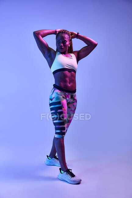 Muscular African American female athlete with sweaty body showing biceps on blue backgroun — Stock Photo