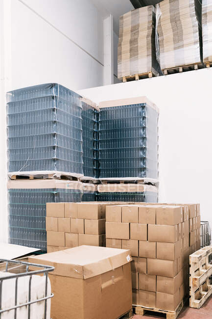Warehouse with heaps of carton boxes and plastic containers with bottles of beer in factory — Stock Photo