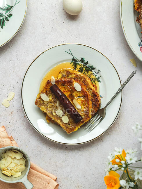 Сверху вкусные французские тосты наливаются медом и украшаются миндальными хлопьями, которые подаются на стол на завтрак. — стоковое фото