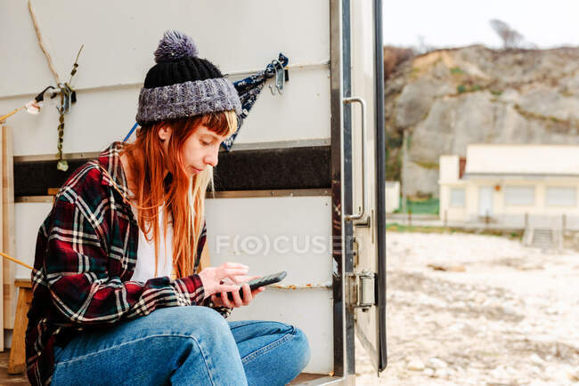 Vista lateral da mulher viajando sentado no caminhão e mensagens no telefone móvel — Fotografia de Stock