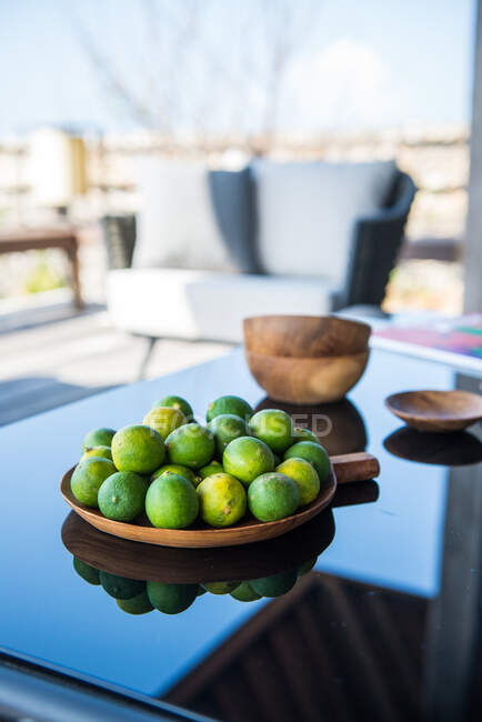 Exotic green mangoes on plate served on table with rip limes on sunny day in tropical resort - foto de stock