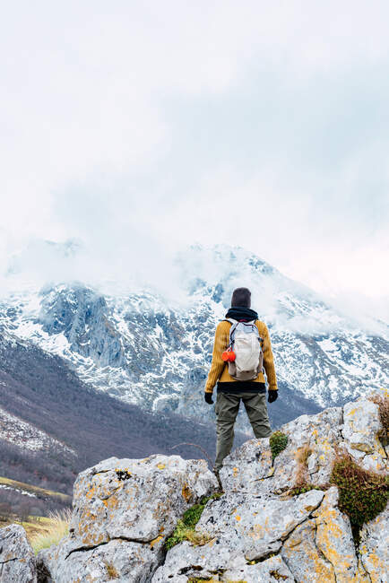 Visão traseira do caminhante com mochila e em roupas quentes em pé no cume rochoso do vale em Peaks da Europa e olhando para longe — Fotografia de Stock