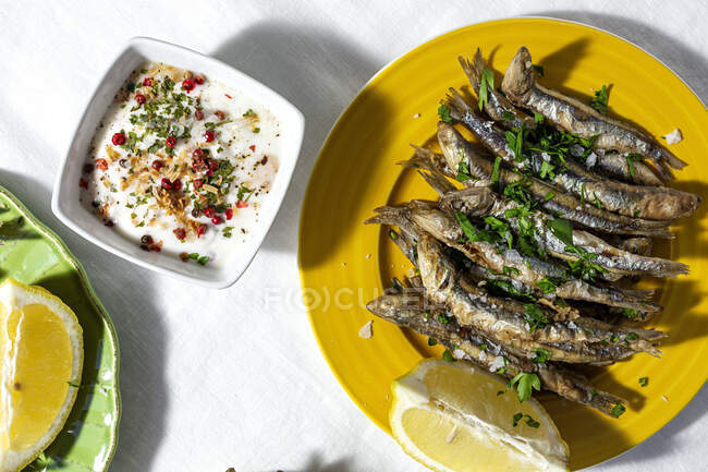 From above of traditional Spanish fried boquerones served on plates with lemons and bowl of white soup placed on table in restaurant — Foto stock