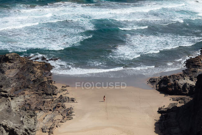 Вигляд анонімної жінки - мандрівника, що захоплюється піщаним океаном з піщаного пляжу між горами. — стокове фото