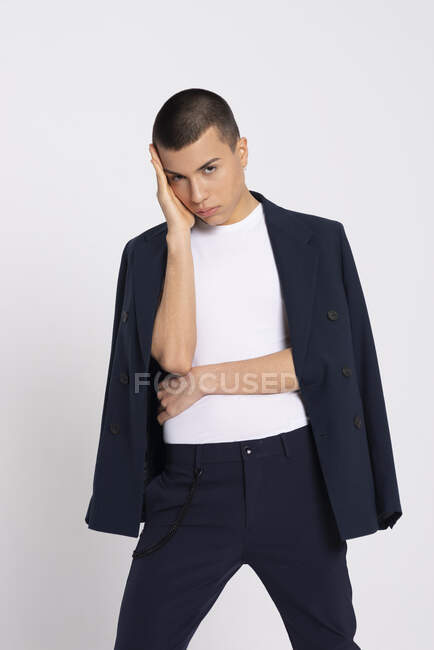 Modelo masculino sério em terno elegante em pé sobre fundo branco no estúdio e olhando para longe — Fotografia de Stock