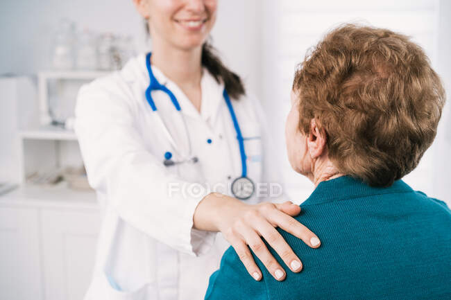 Анонімний лікар, який розмовляє з літньою жінкою, дивлячись один на одного під час огляду в лікарні — стокове фото