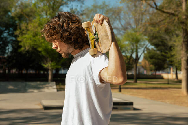 Profil de skateboarder tenant sa planche sur ses épaules — Photo de stock