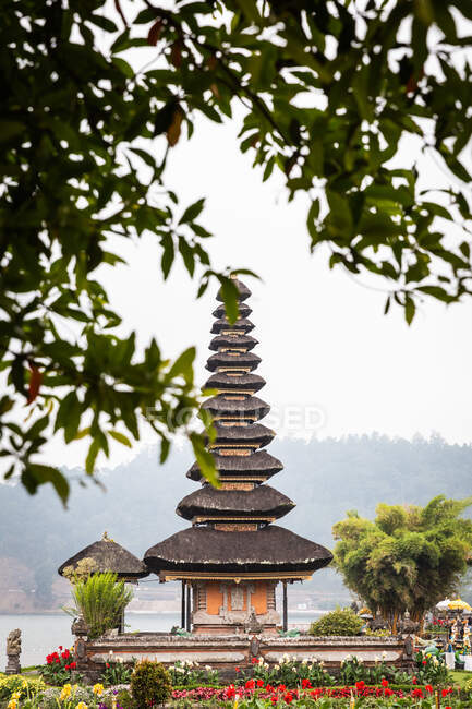 Exterior del templo de Uluwatu con techo ornamental situado en el jardín floreciente en Bali - foto de stock