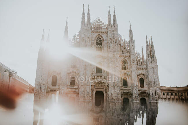 Зовні старовинна кам'яна церква з орнаментом між будинками під сяючим небом у Мілані (Італія). — стокове фото