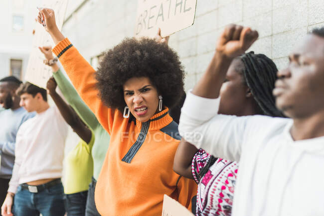 Young African American woman with afro hair standing with fist up protesting during Black Lives Matter demonstration in city — Foto stock