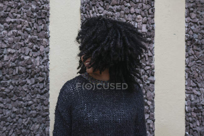 Зміст етнічної жінки з африканською зачіскою, що кидає волосся, стоячи на вулиці і посміхаючись — стокове фото
