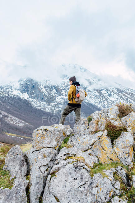 Назад погляд на туриста з рюкзаком і теплим одягом, що стоїть на скелястому кряжі долини в Піках Європи і дивиться у далечінь — стокове фото