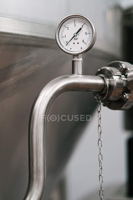 Manómetro con flecha y números en tubo de acero inoxidable de recipiente profesional en fábrica de cerveza - foto de stock